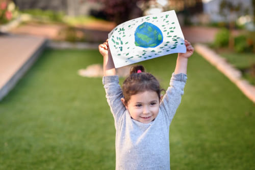 A child holding a drawling of the world above their head