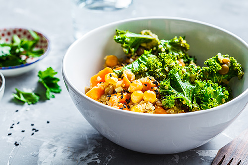 Vegan stew with chickpeas, sweet potato and kale in a white bowl