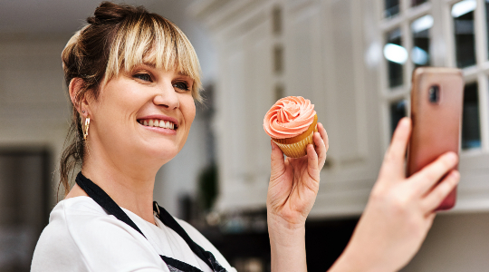 Happy woman taking selfie with cupcake 
