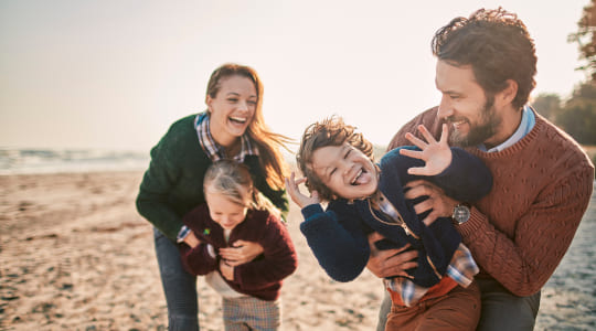 Photo of a smiling family playing on the beach in the sun