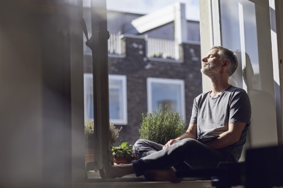 person relaxing by the window looking at the sun shine