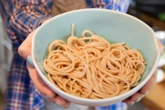 person holding a bowl with a portion of pasta
