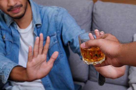 person saying gesturing no to an alcoholic drink
