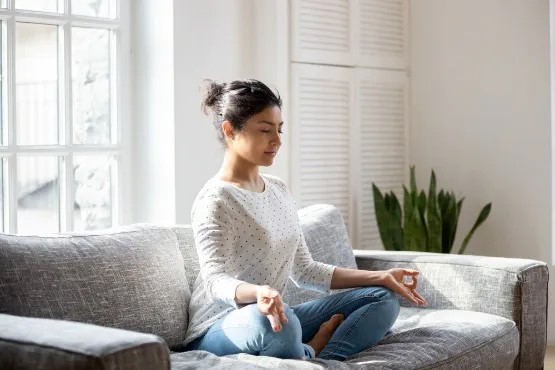 woman meditating on a sofa