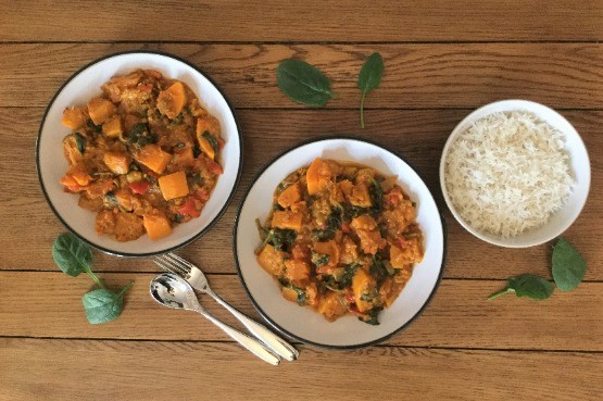two bowls of vegan coconut curry and a bowl of rice with cutlery