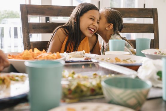 Sisters whispering at dinner