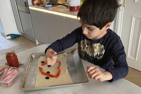 a little boy making pizza at home