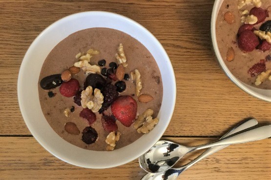 Two bowls of chia chocolate chia pudding with berries and nuts