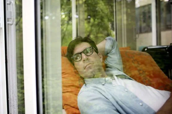 a man lying down, looking out of the window