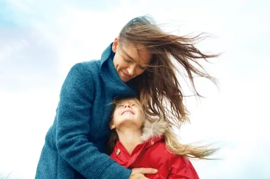 woman holding a girl on a windy day