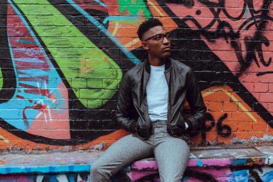 man sitting against a graffiti wall