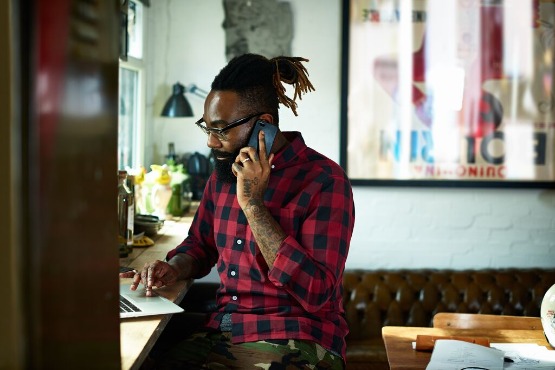 Man on working on a laptop and talking on a phone