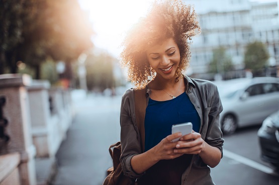 woman walking outdoors looking at her mobile phone