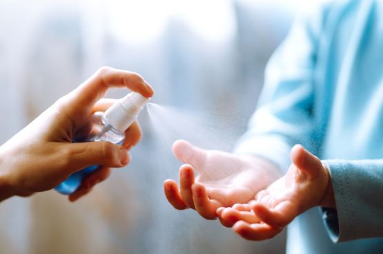 person spraying hand sanitiser on a child's hand