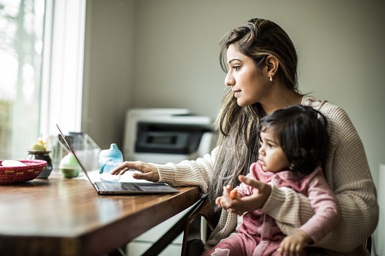woman with a baby on lap checking laptop