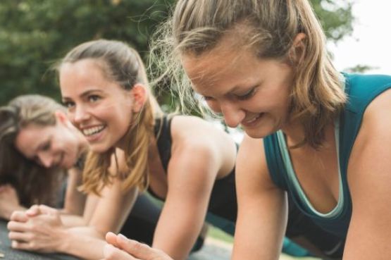 group of women doing plank exercise outdoors