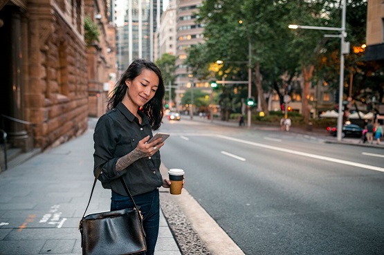woman checking her phone waiting on a footpath