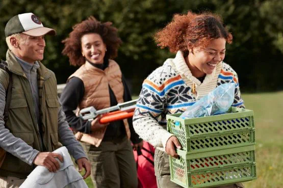 three people carrying food for a picnic