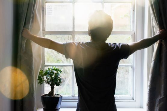person opening curtains in the morning