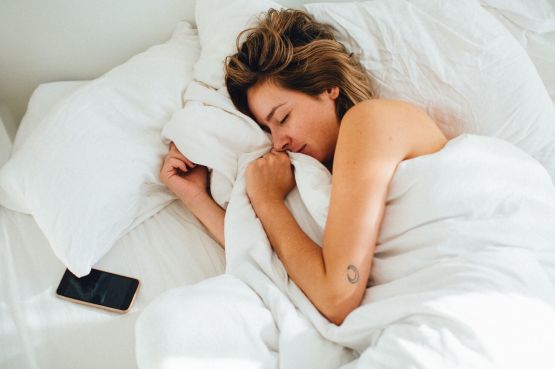 woman sleeping in bed with phone next to her