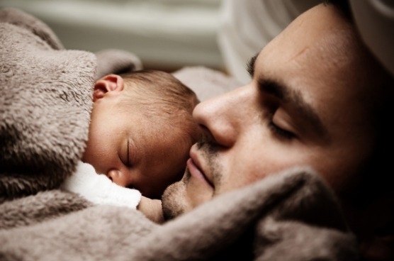 new born baby sleeping on father's chest