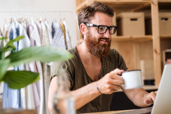person with coffee browsing on a laptop