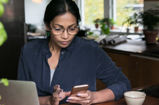 woman working on a laptop and messaging on mobile
