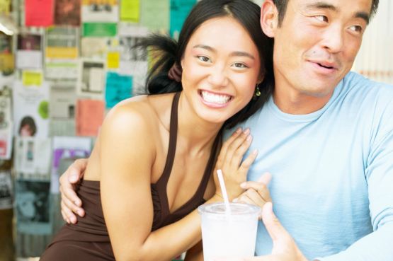 two people laughing with a milkshake in hand