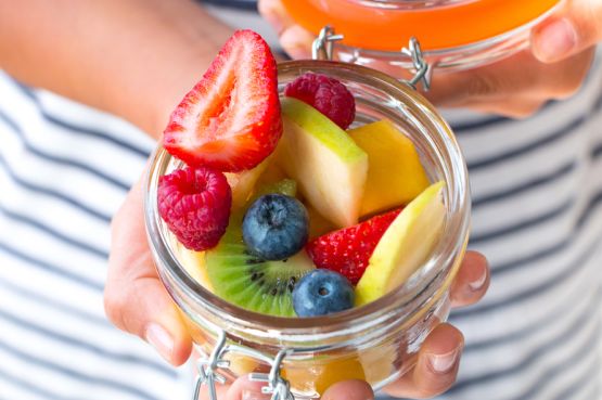 person holding out a bowl of fruit