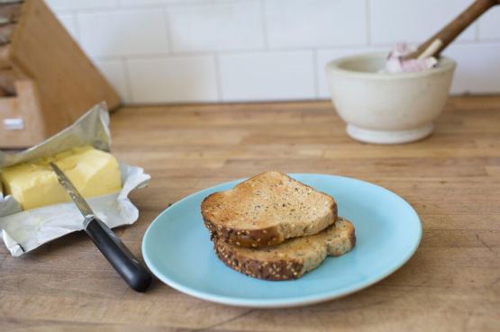two pieces of toast on a plate with a stick of butter next to it