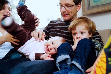 adults and toddlers laughing, playing on the sofa