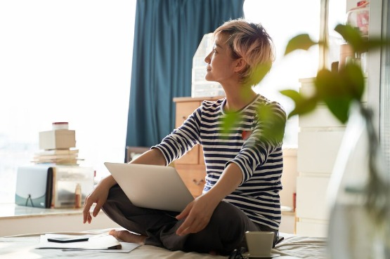 person sitting with folded legs with laptop on lap