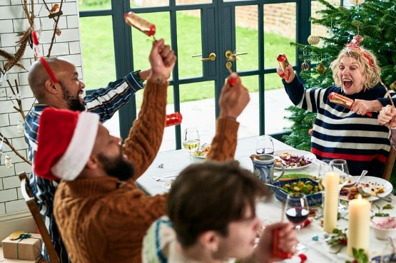 group of people pulling crackers around a Christmas meal