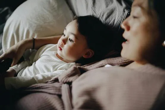 person and child lying in bed