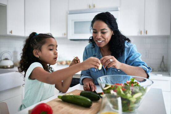 adult chopping and cooking courgettes with a toddler