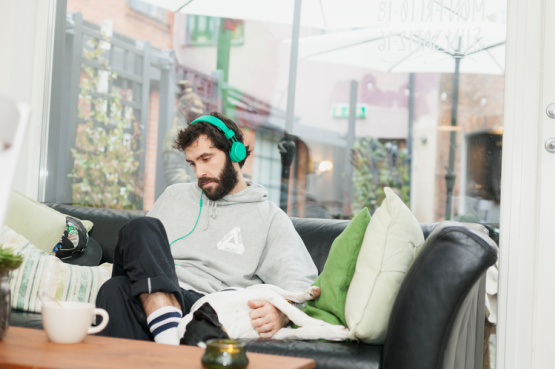 man relaxing on the sofa with headphones on