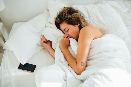 person sleeping by a mobile phone in bed
