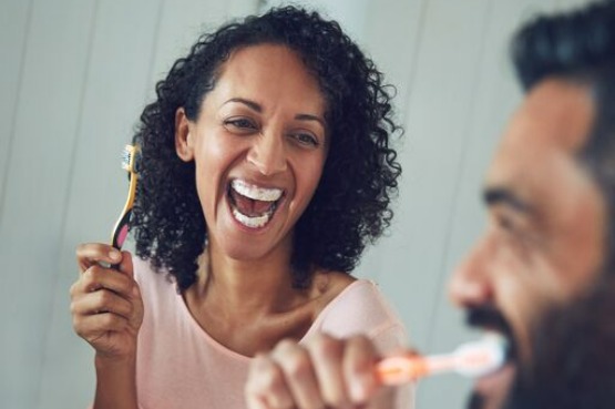 two people laughing while brushing teeth