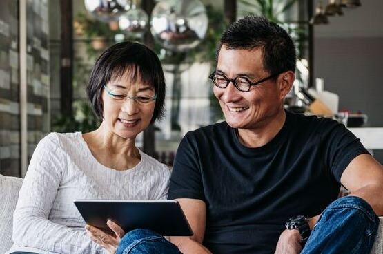 two people on a grey sofa with a tablet