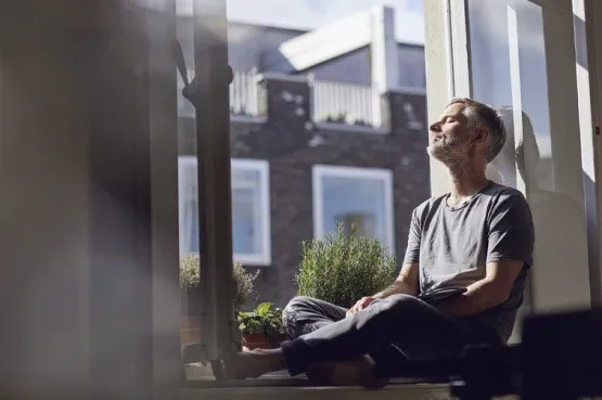 person relaxing by the window looking at the sun shine