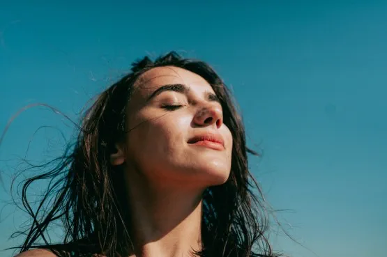 person with eyes closed in outdoor sun