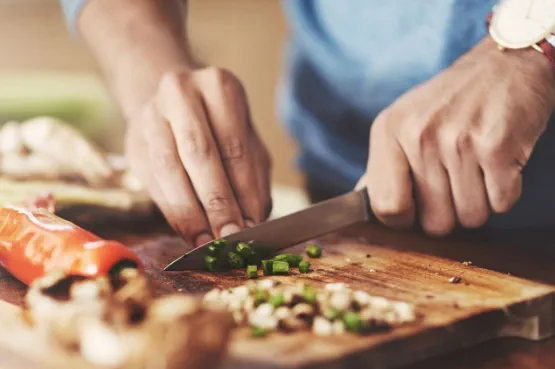 An imager of hands chopping vegetables on a chopping board