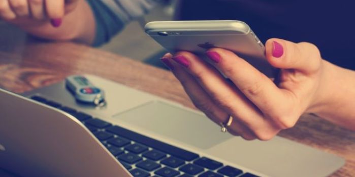 A lady on her phone and working at a laptop
