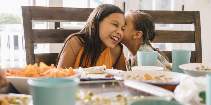 Sisters whispering at dinner