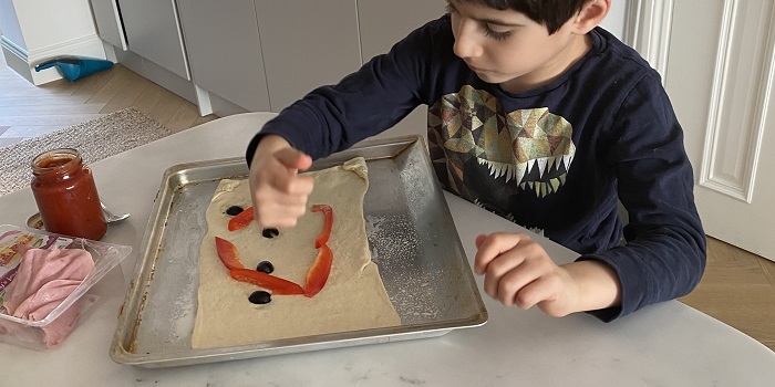 a little boy making pizza