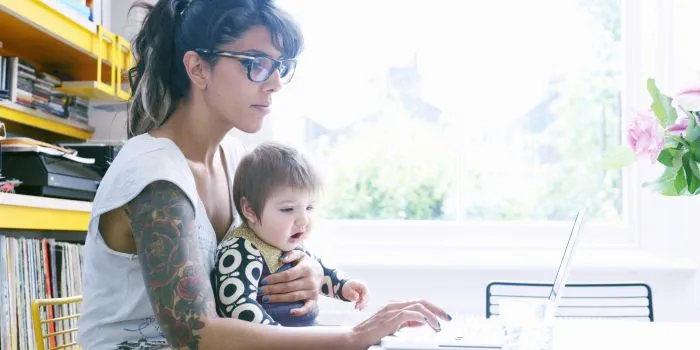 lady with a toddler on lap, working at a laptop