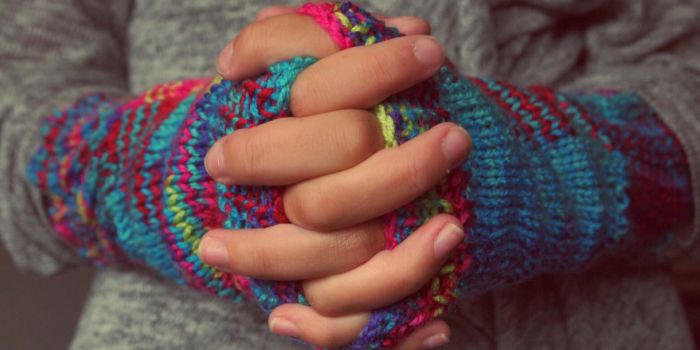 an image of a person's folded hands, wearing colourful gloves