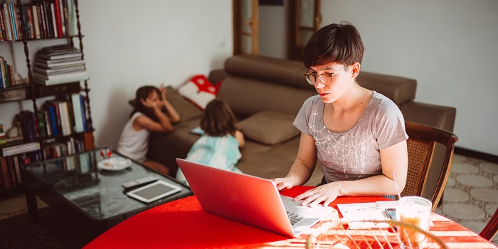 woman working on the laptop with glasses, children in background