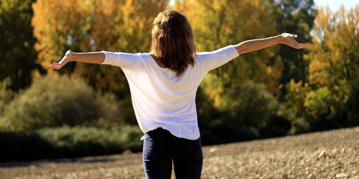 a woman standing outdoors with arms stretched