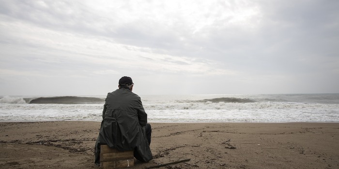 man sitting at the beach watching the sea